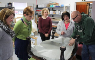 Students look on in this hands-on upholstery workshop as Kim demonstrates